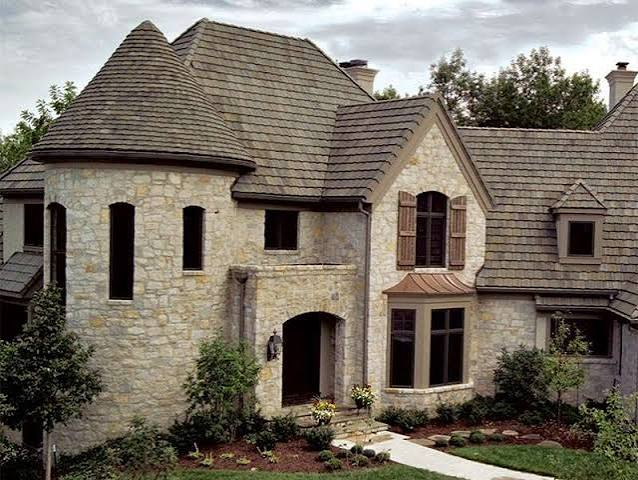Large stone home with a flat-profile concrete tile roof