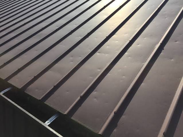 Long metal roof panels with scattered shallow hail dents