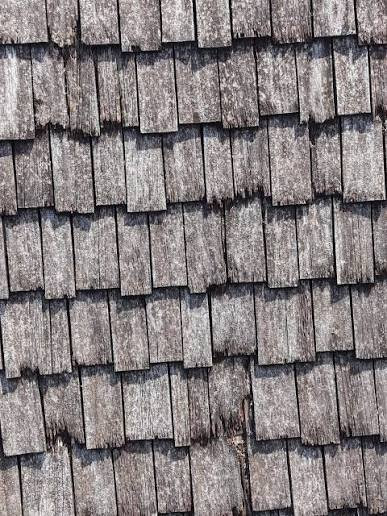 Weathered gray wood shake roof with worn and split edges